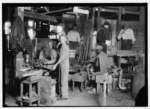 Lewis Hine child labor: Cumberland Glass Works, Bridgeton, N.J. A young "holding-mold boy" is seen, dimly, in middle distance to left of centre. Negroes, Greeks and Italians are being employed in many glass houses. Location: Bridgeton, New Jersey.