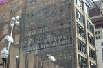 Closeup of American Luxfer sign painted on side of building
